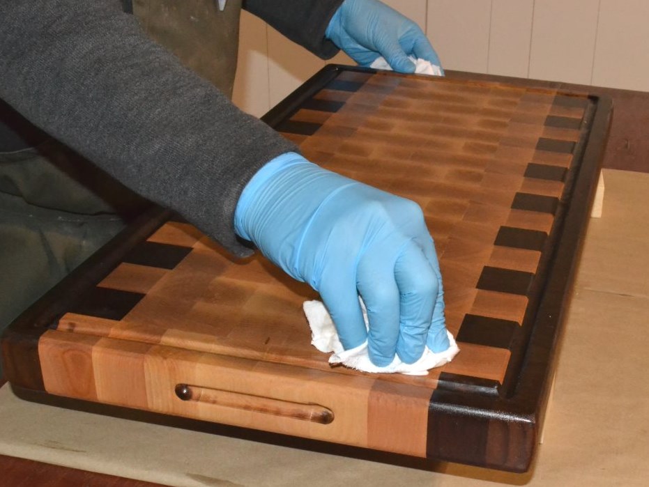 persons hand wearing glove wiping bitcher block board